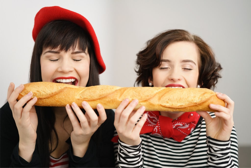 fun-young-french-ladies-biting-into-a-baguette-picture-id1135690903.jpg