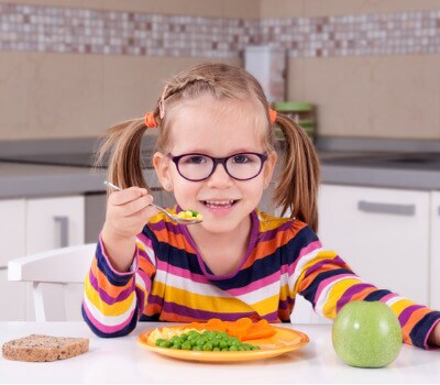 Kind mit Teller voll Gemüse lacht 
