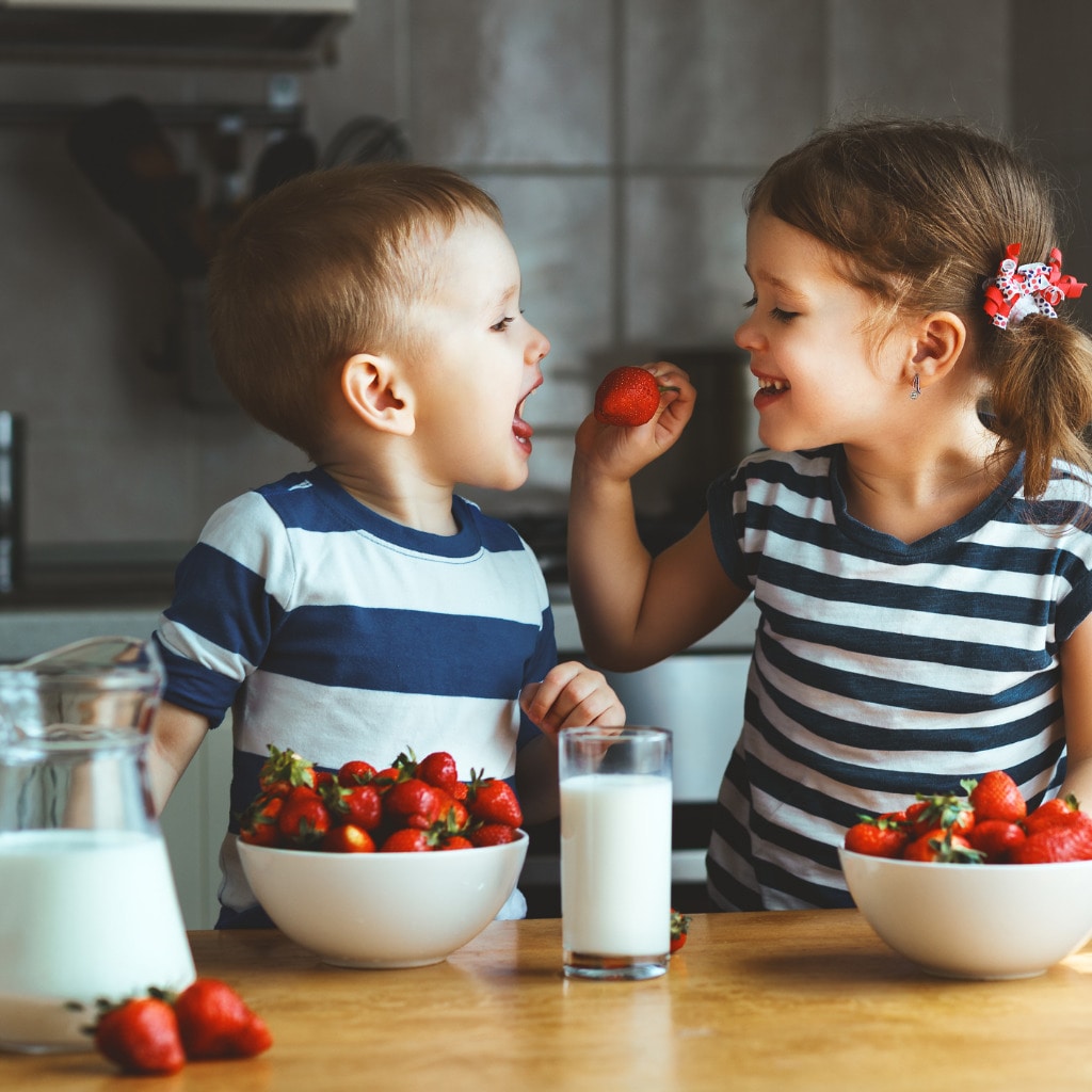 happy-children-brother-and-sister-eating-strawberries-with-milk-picture-id835970896.jpg