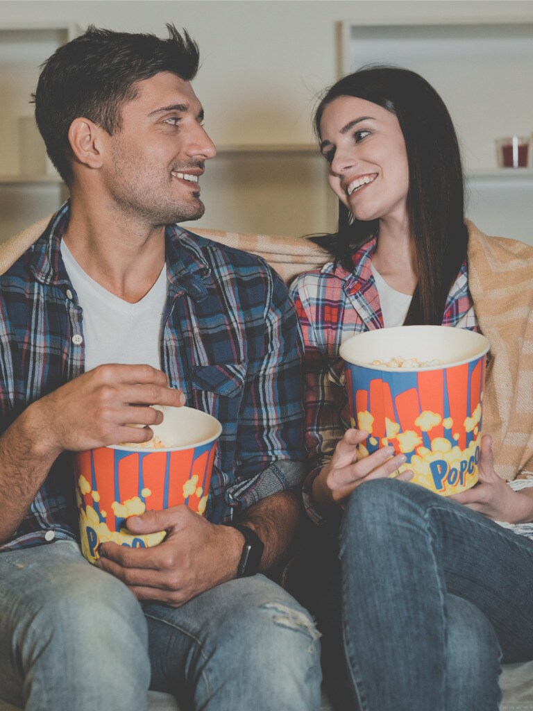 the-happy-man-and-a-woman-eating-popcorn-and-watching-movie-on-the-picture-id1047784084.jpg